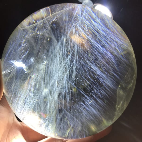 Citrine sphere showing feathery needle sprays and a bright reflection