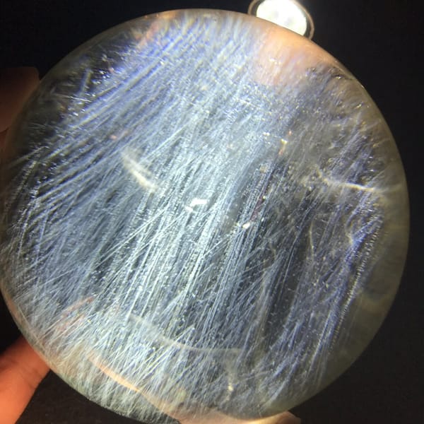 Long silky needles sweeping diagonally across the citrine sphere