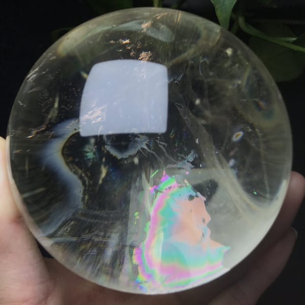 Broad pink and green rainbow and dark curved inclusion in the citrine sphere