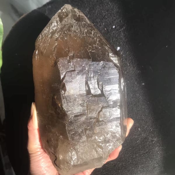 Citrine held in hand showing stepped skeletal texture and smoky colour
