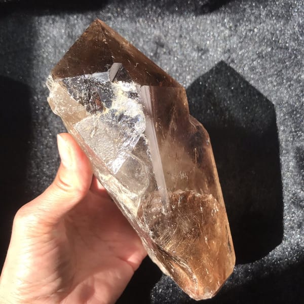 Side face catching a sharp reflection, rutile tufts gathered near the base