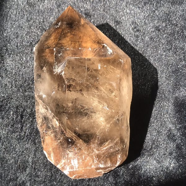 Full front of the smoky citrine point lying on black velvet