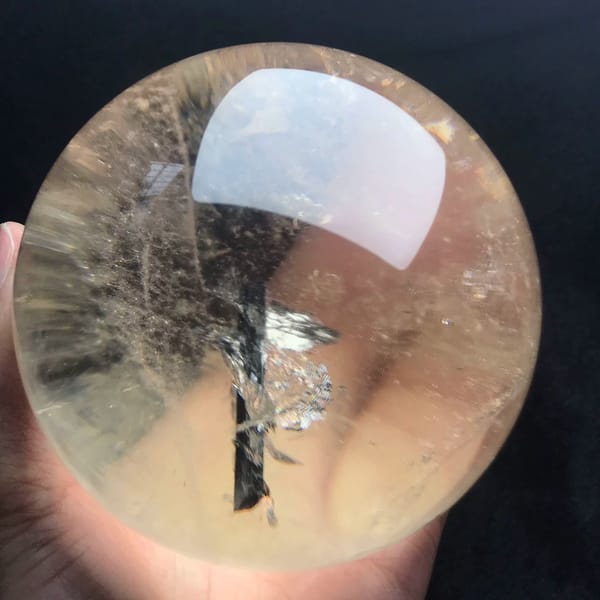 Black needle rising through the sphere with glittering flakes along its length