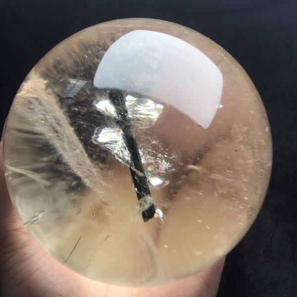 Warm champagne tint visible as the sphere sits in an open hand