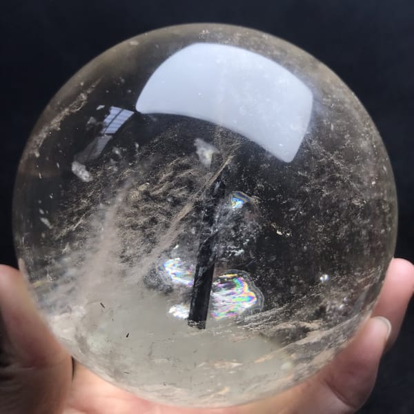 Rainbow flash beside the black tourmaline needle inside the pale sphere