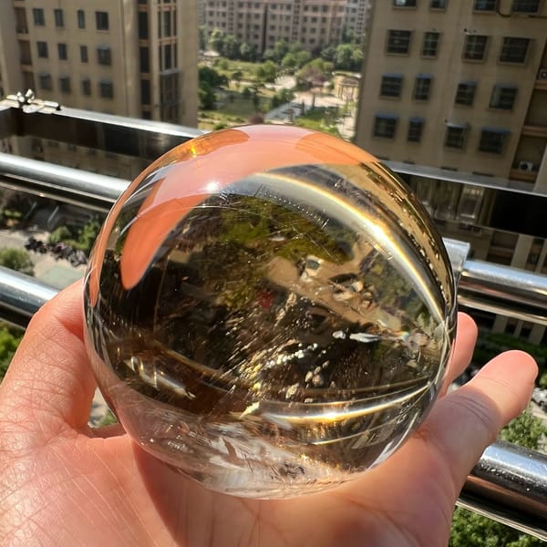 Sphere held on a sunny balcony, city view inverted inside the clear quartz