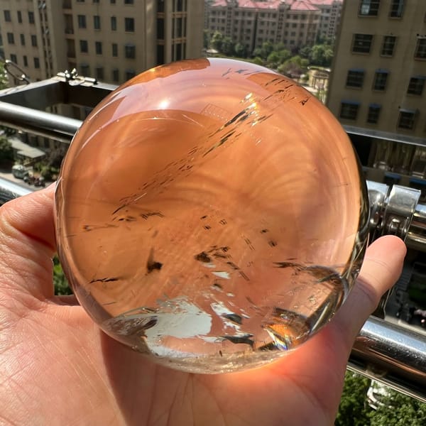 Warm peach-toned view of the sphere with fine dark flecks in the lower half