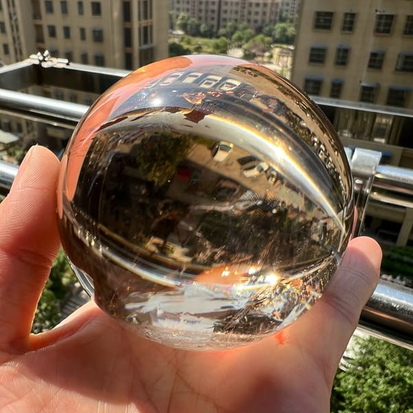 Tea-coloured sphere in sunlight reflecting buildings and a bright rim of light