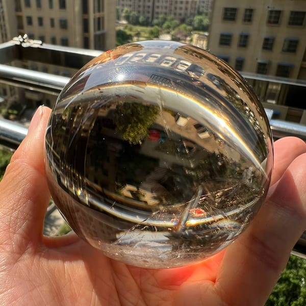 Clear smoky citrine ball showing an upside-down reflection of trees and railings