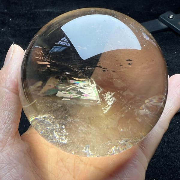 Sphere indoors on dark cloth with a small rainbow in its lower half