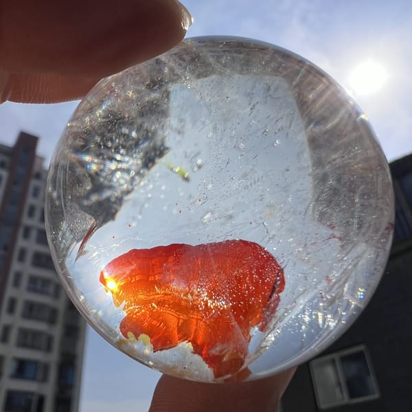 Backlit view of the bright red inclusion with tiny yellow flecks nearby