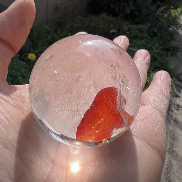 Sunlit sphere in a palm, red inclusion and bright flare beneath