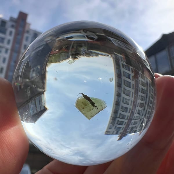 Sphere held to the sky, heart-shaped mica flake set against inverted buildings