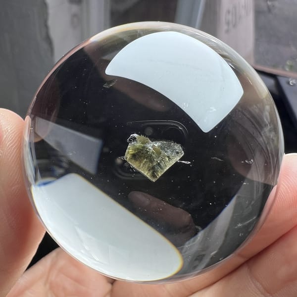 Clear sphere with a broad white reflection and the green heart below it