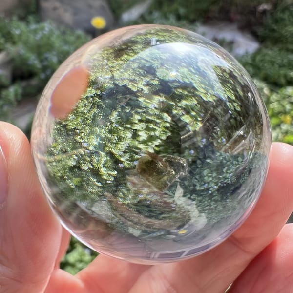 Clear sphere held over garden greenery, mica heart softly visible inside