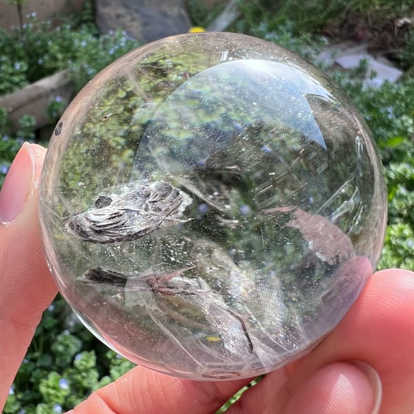 Flat silvery mica cluster lying across the sphere like a small cloud