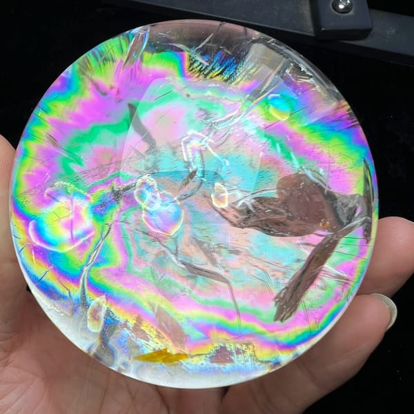 Clear quartz sphere on black, nearly covered by concentric vivid rainbow rings
