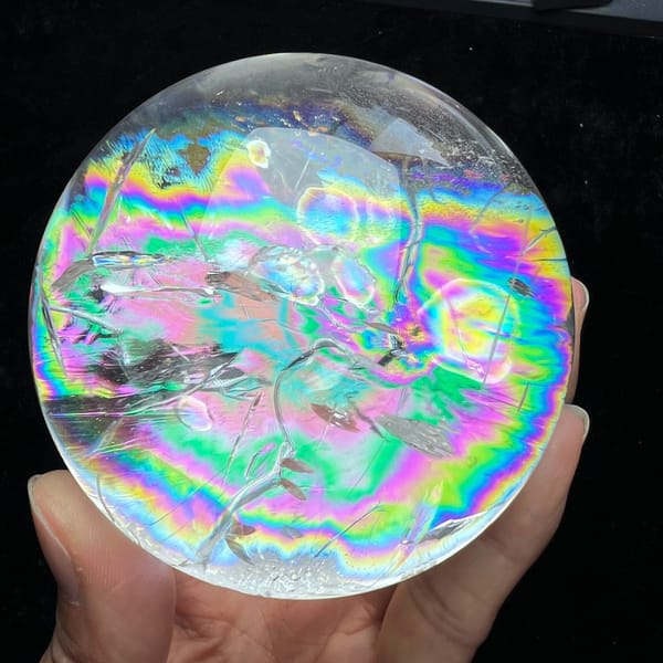 Rainbow bands in pink, green and gold rippling through the Himalayan sphere