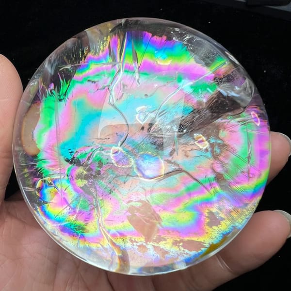 Rainbow-filled sphere with fine silvery fracture lines across the colour