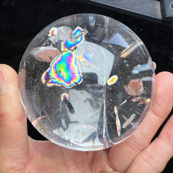 Clear side of the sphere with one rainbow patch and pale inclusions
