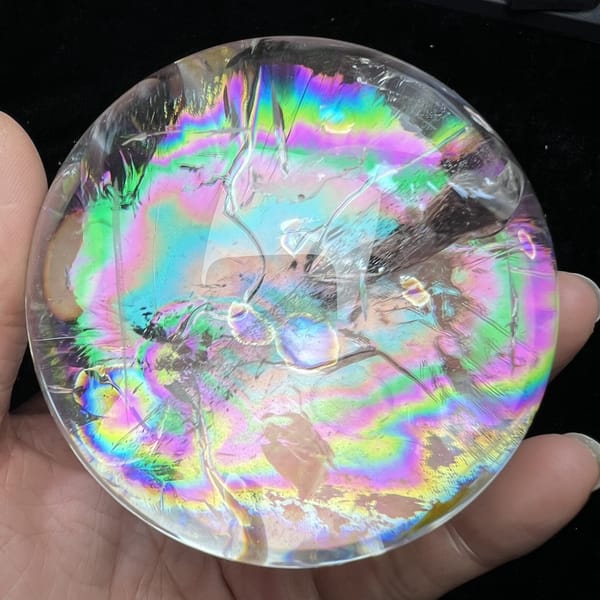 Sphere held in hand with rainbows spreading to the polished edge