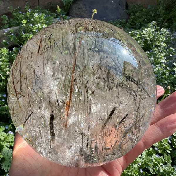 Amber and olive mica blades filling the sphere against garden greenery