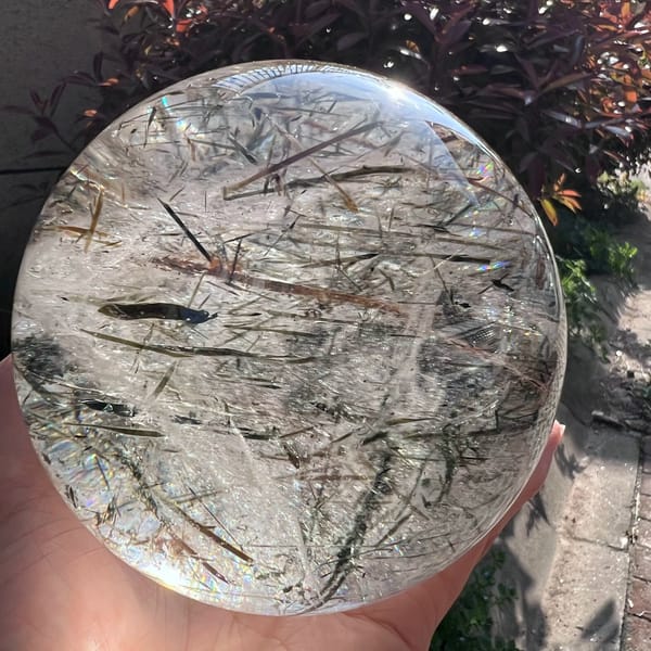 Horizontal view of tangled green and brown mica blades inside clear quartz