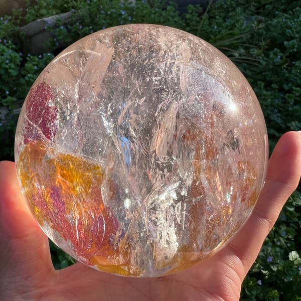 Red branch-like inclusions above golden yellow patches inside the sphere