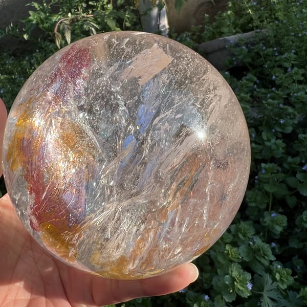 Feathery white veils and pale red inclusions near the sphere edge