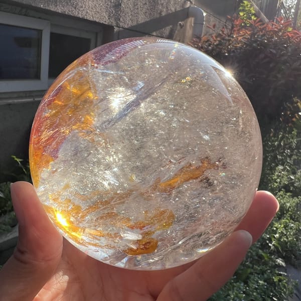 Golden yellow inclusion trails curving through the clear sphere