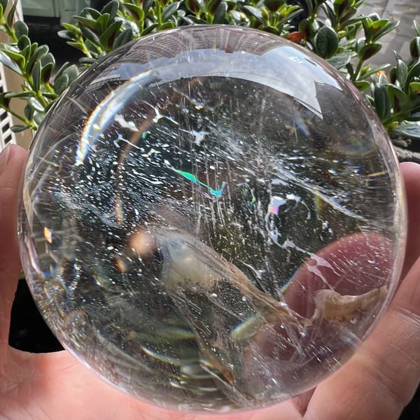 Himalayan quartz sphere sparkling with fine needle glints and a small rainbow