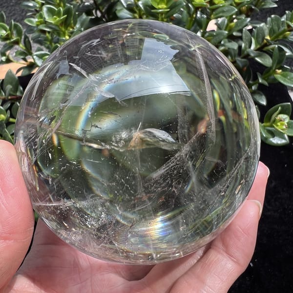 Clear sphere showing a faint rainbow arc and thin inclusion lines