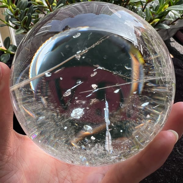 Large quartz sphere with long tourmaline needles and a rainbow arc at its edge