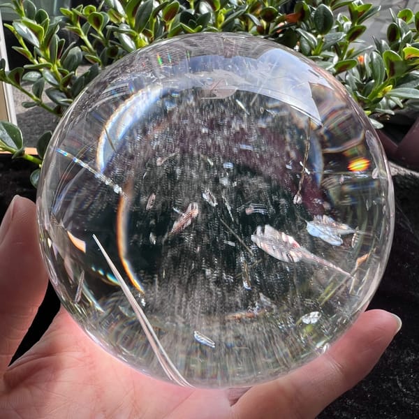 Fine green tourmaline needles crossing the clear sphere above a misty base