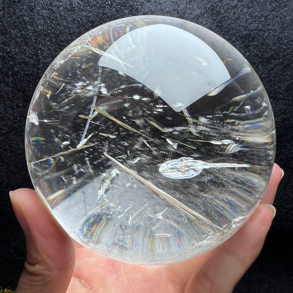 Sphere on black with a long needle and a leaf-shaped inclusion below the highlight