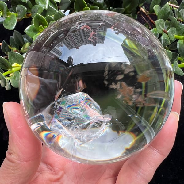 Clear Himalayan sphere with a large included crystal showing rainbow banding
