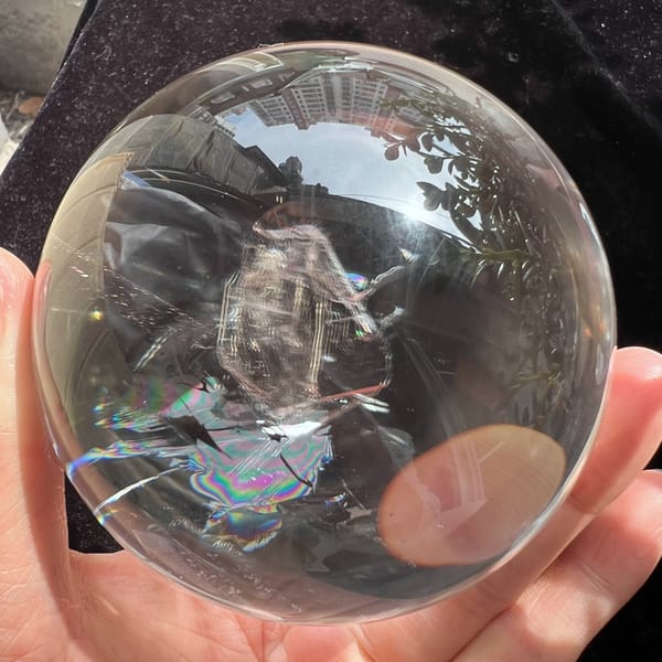 Included crystal standing upright with rainbow flare and a warm edge reflection