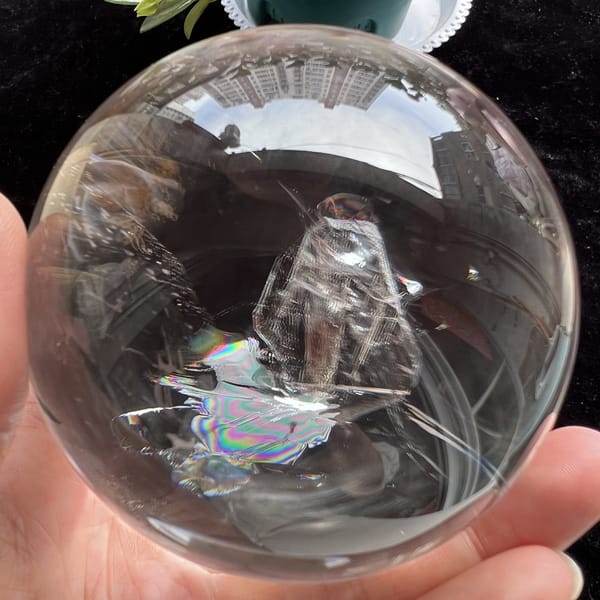 Tall included crystal with a rainbow ribbon beneath, sphere held in a garden