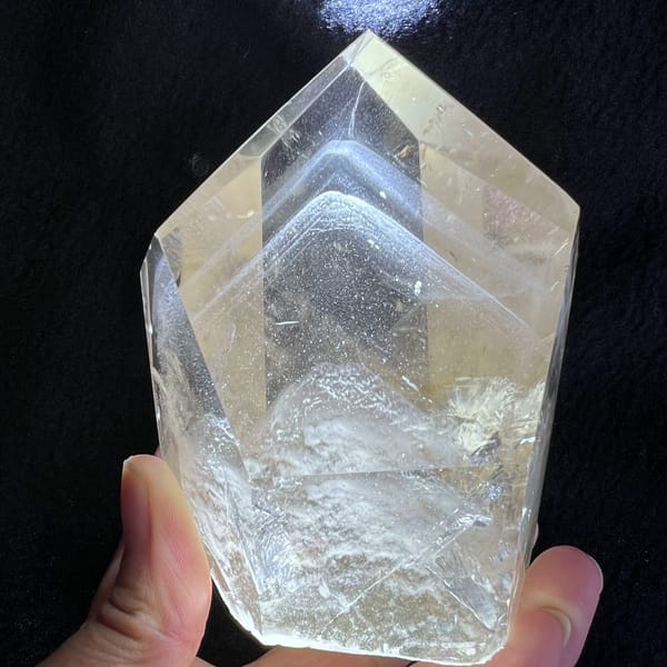 Clear quartz tower on black with nested white phantom outlines inside the tip