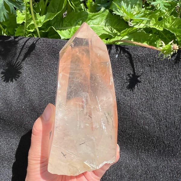 Tower against black cloth in sunlight, red inclusions and dark needles visible