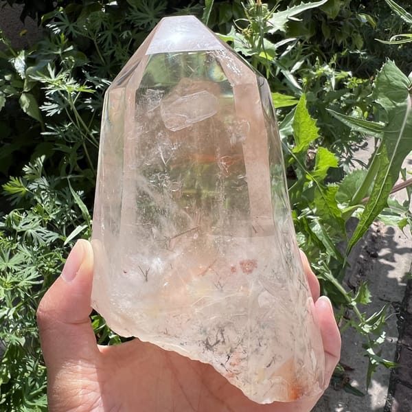 Rough broken base edge with red inclusions and needle crosses inside clear quartz