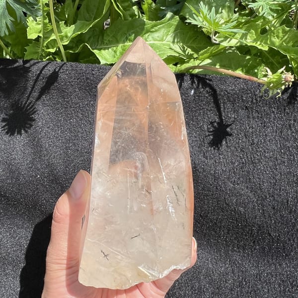 Black cloth backdrop highlighting fine needles and pale red veils in the quartz