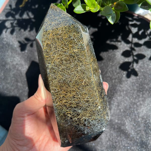 Sunlit tower on dark cloth, golden rutile glowing like woven straw