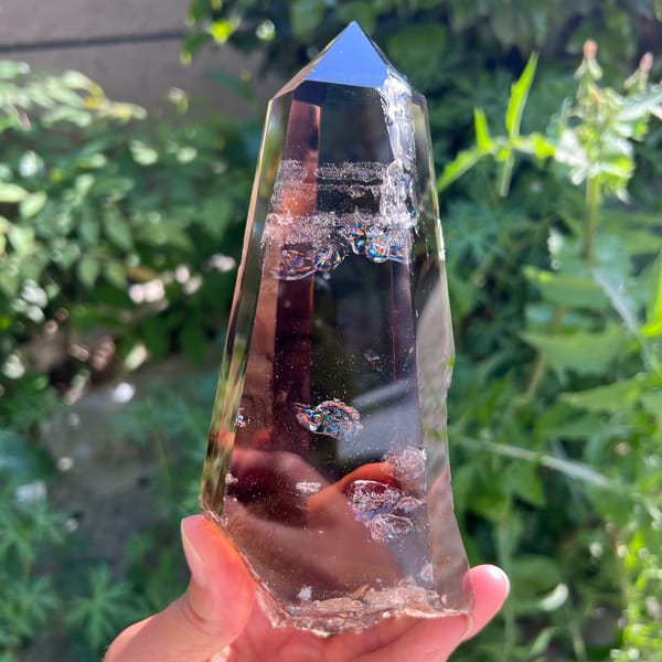 Smoky quartz laser point with white veils and rainbow flashes near the top