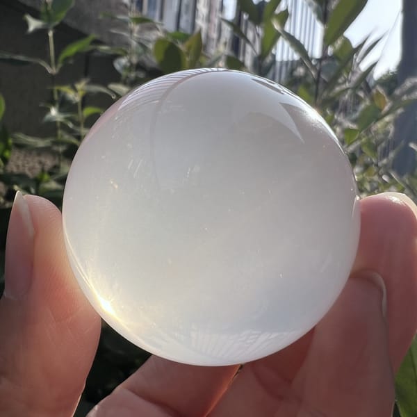Sphere between fingers in shade, smooth icy milky polish