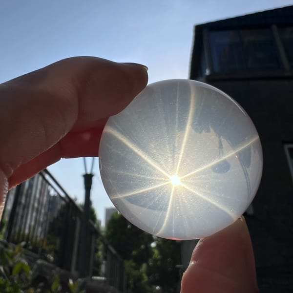 Small milky quartz sphere held to the sun, six-ray star glowing
