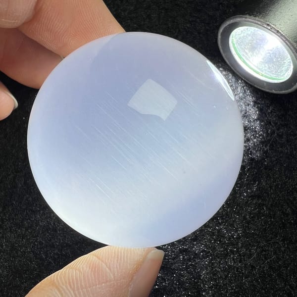 Sphere under a small lamp on dark cloth showing silky sheen