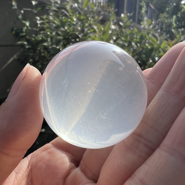 Sphere resting in palm with soft white translucence