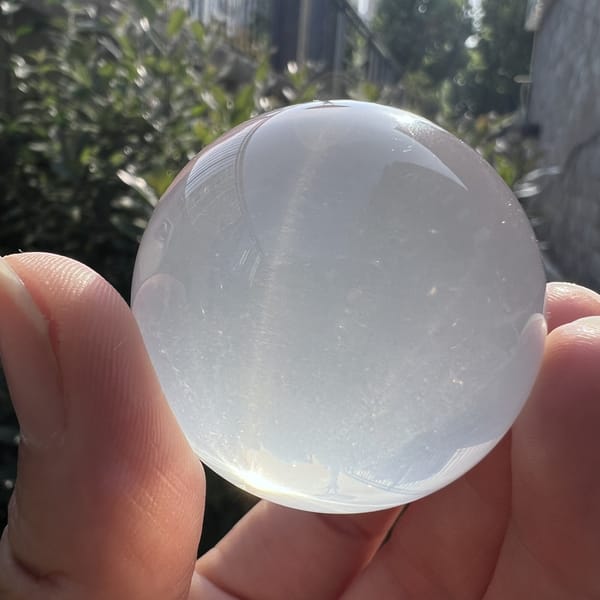 Front-lit sphere between fingers with silky milky sheen