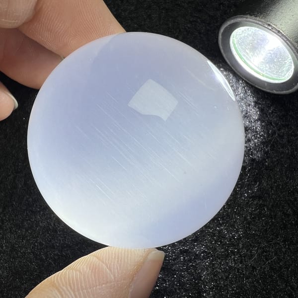 Lamp-lit sphere on dark cloth with fine needle sheen